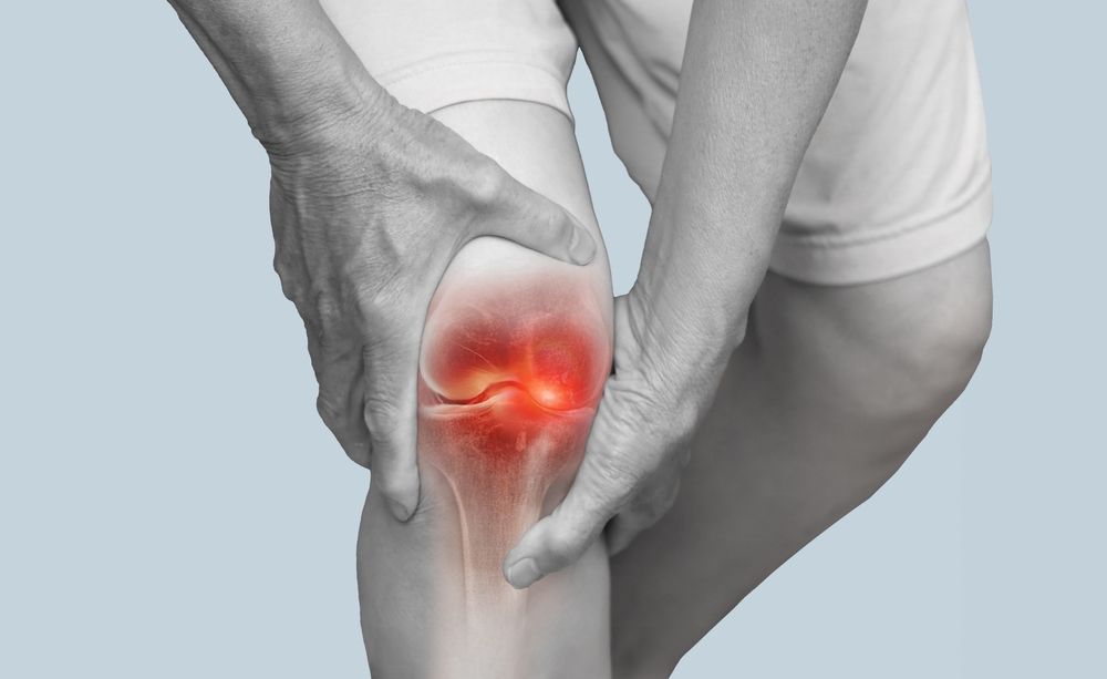 Person holding knee, highlighting pain and inflammation. Red glow indicates injury.