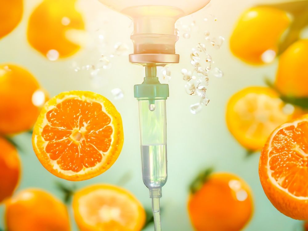 IV drip dispensing clear liquid with oranges in the background.