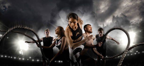 Athletes working out on a stadium under a stormy sky, ropes in hands.