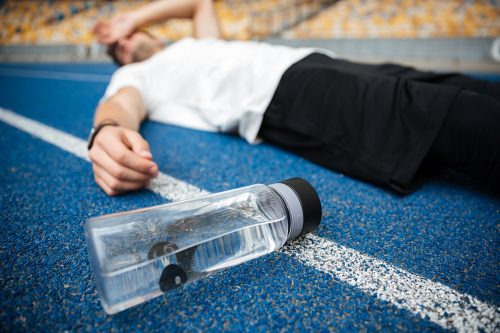 Man collapsed on a track next to a water bottle.