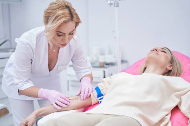 Nurse administering IV to patient's arm in a medical setting.