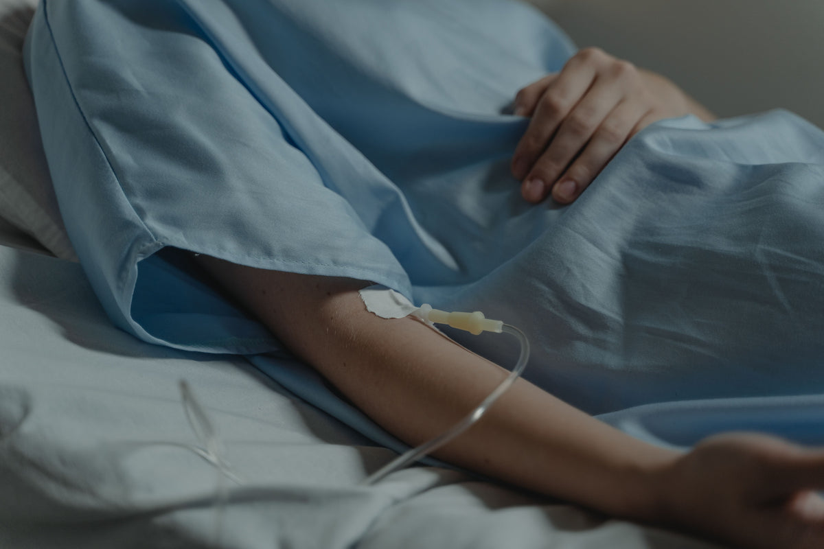 Person in hospital bed with IV in arm.