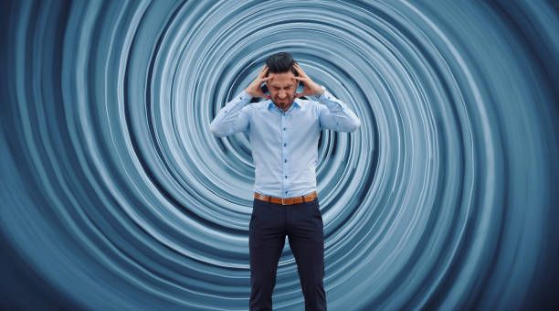 Man with hands on head in front of swirling blue background.