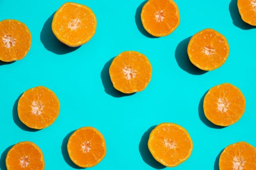 Orange citrus fruit halves arranged on a teal background.