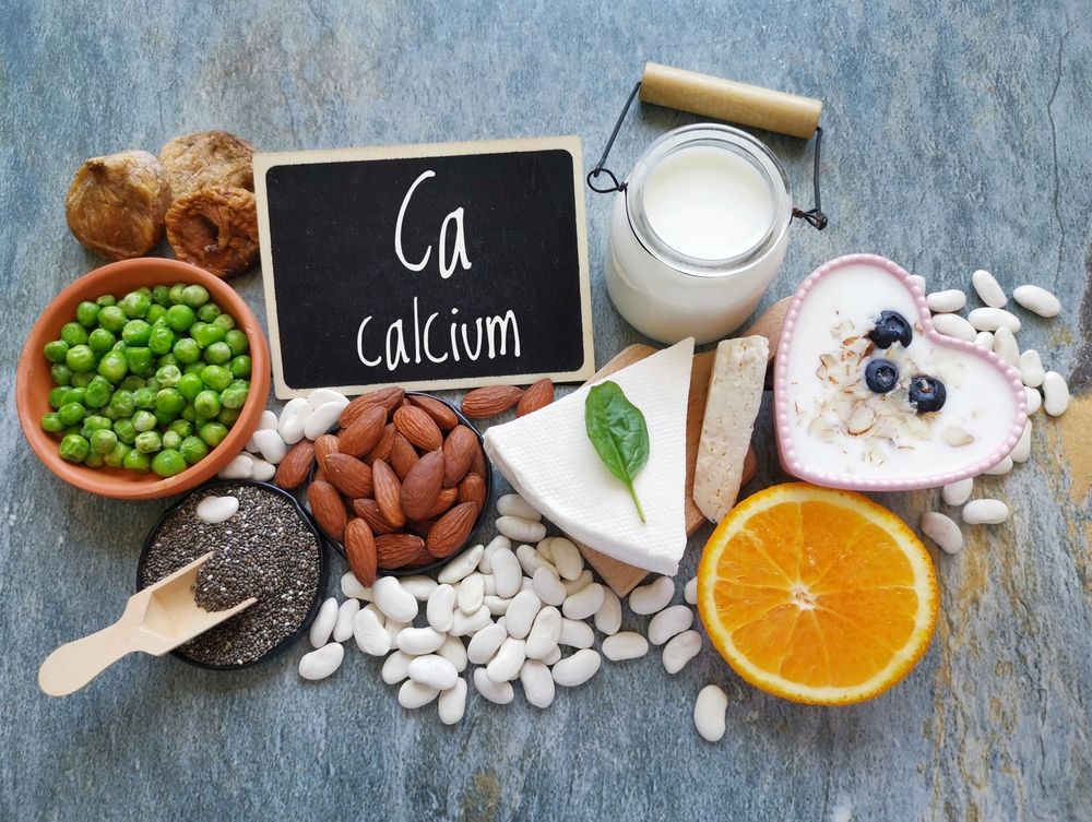 Foods rich in calcium: peas, bread, yogurt, cheese, almonds, chia seeds, beans, orange, and blackboard with