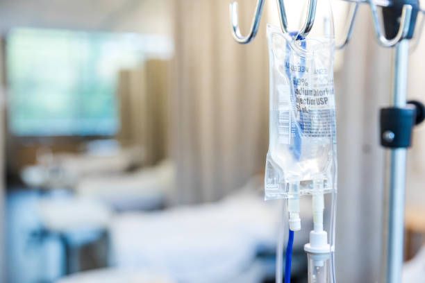 IV drip bag hanging in a hospital room, blurred background.