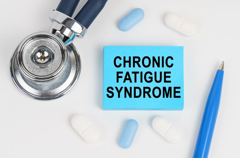 Stethoscope, pills, and pen next to a blue note that reads “CHRONIC FATIGUE SYNDROME”.