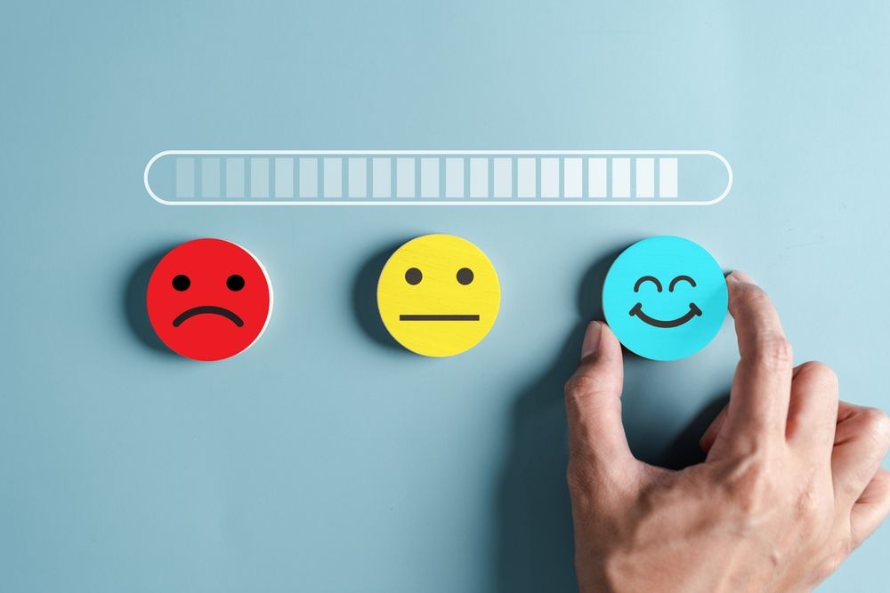 Hand selecting happy face to complete satisfaction survey.