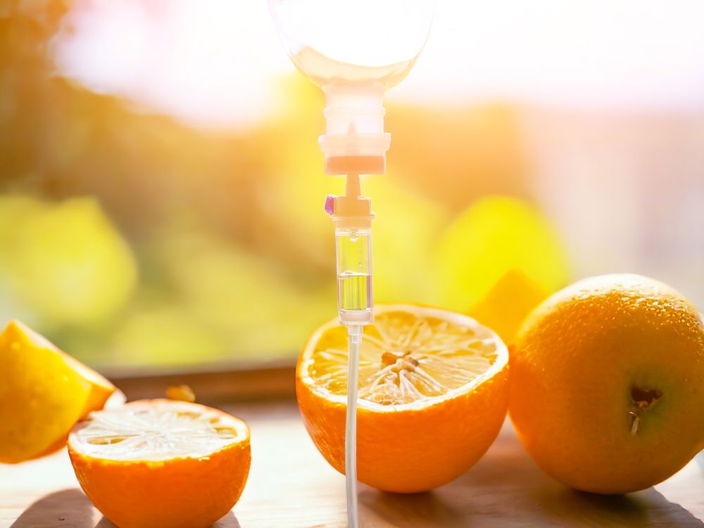 IV drip with oranges, lemons, and sunlight background.