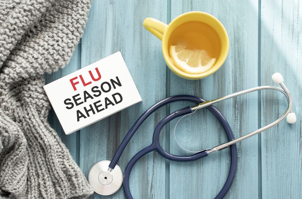 Flu season reminder with scarf, lemon tea, and stethoscope.
