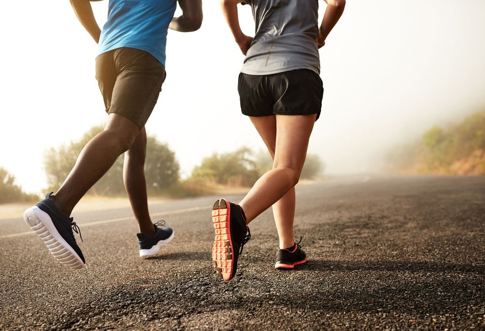 Two people running on a paved road, toward a foggy horizon.