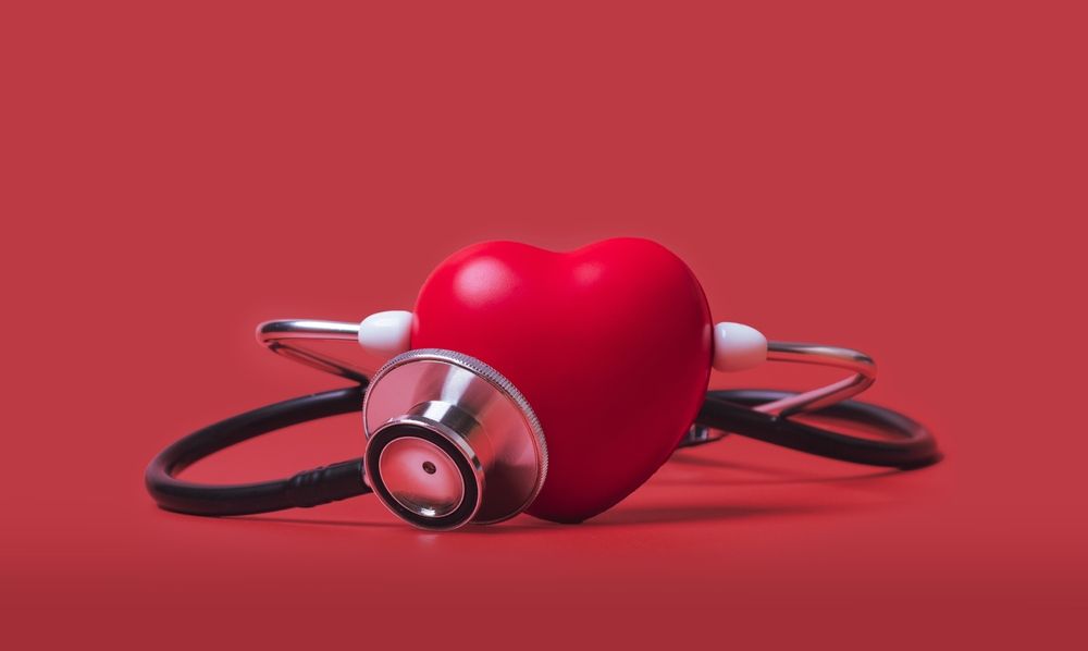 Red heart with a stethoscope around it on a red background.