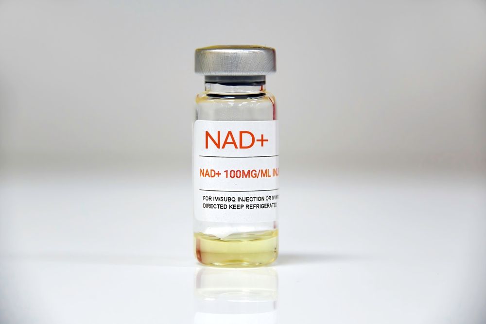 Vial of NAD+ solution with red text label; clear glass with silver cap, light background.