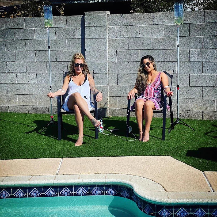 Two clients receiving mobile IV therapy poolside in Scottsdale